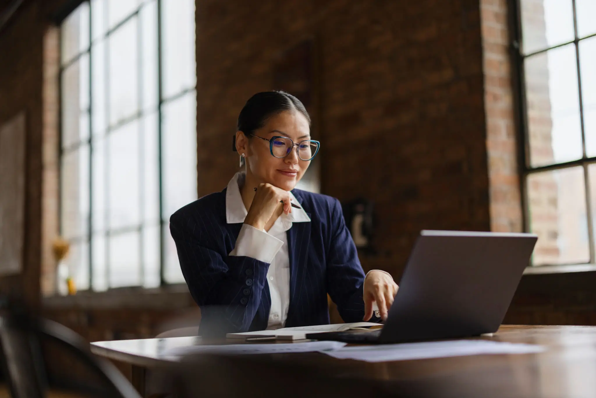 A focused woman working on a laptop in a cozy office.