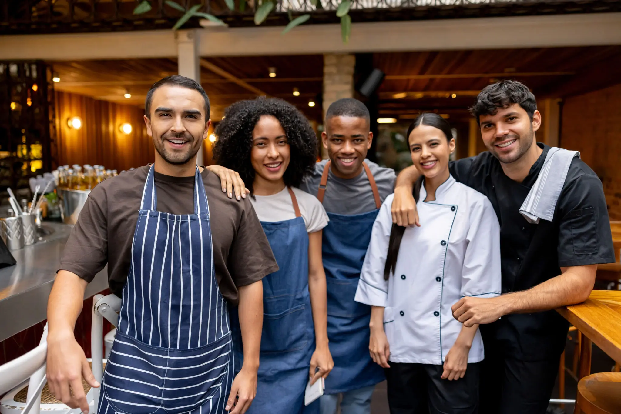 A diverse group of happy restaurant staff posing together outdoors.
