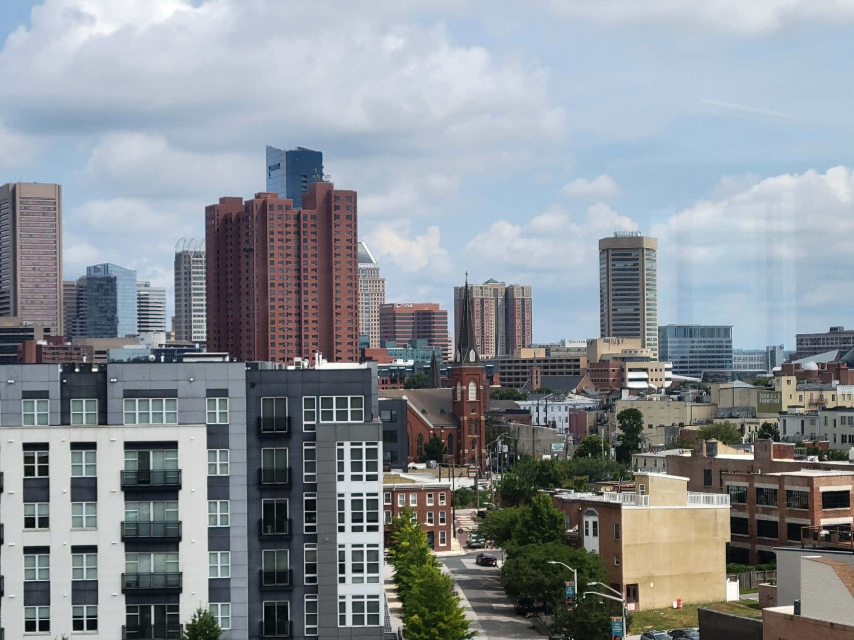 Urban cityscape with a mix of modern and older buildings under a cloudy sky.